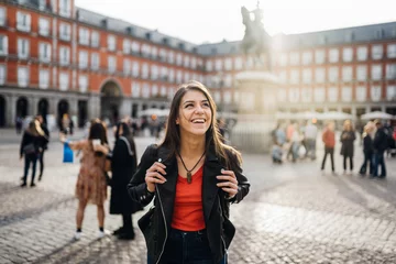 Deurstickers Young travel woman sightseeing urban outdoors.Traveling to Europe. Walking tour in Madrid.Backpack tourist experience.City girl.Cheerful tourist.Visiting Plaza Major square © eldarnurkovic