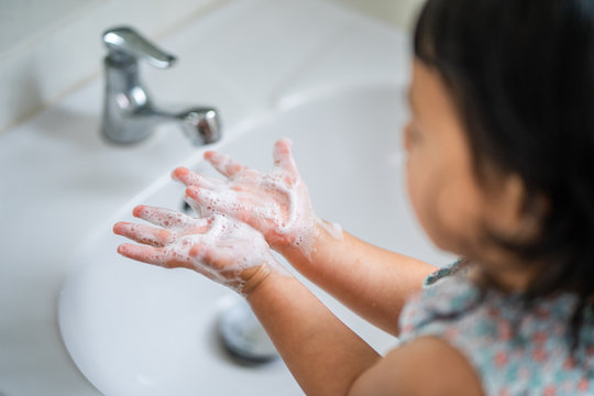 Little Girl is washing her hands to prevent virus and germs.