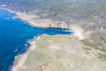 Obraz premium The seemingly peaceful Pacific Ocean washes against the rocky Northern California coastline on a beautiful day. This part of the west coast is known for its inspiring rugged natural beauty.