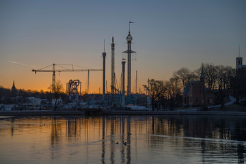 Morning skyline view at sunrise over the district Djurgården with boats, ice and towers in orange back light in Stockholm.