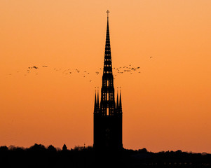 Naklejka premium Morning skyline at sunrise over the old town district Gamla Stan in orange light sky with profiles of houses and churches. 