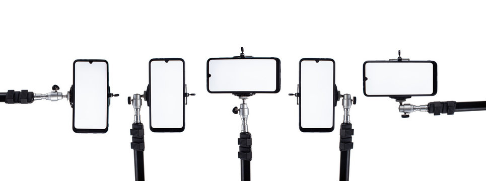 A lot of smartphones mounted on tripods and holders in different positions on a white isolated background.
