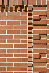 Traditional red and brown brick wall texture background with rows of protruding bricks showing geometric brickwork designs