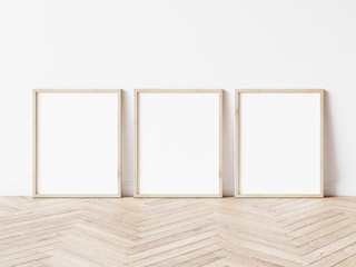 Three vertical wooden frame poster on wooden floor with white wall. 3 frame mock up. 3D illustration.