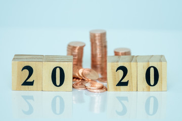 Miniature people: Wooden 2020 and stack of coins with copy space for text using as background saving, investment, money, financial, business analytics concept.