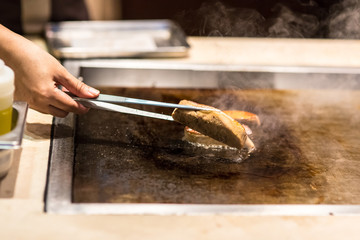 Chef flipping grilled meat on teppanyaki  pan