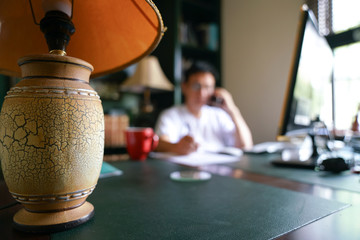 Man working from home. Focus on table lamp.