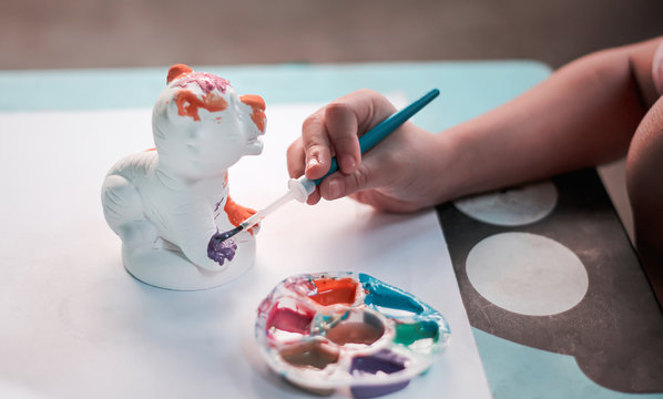 Little Child Asian Girl  Right Hands Painting Color On The Plaster Tiger Statue With Bright Blue Paintbrush And Colorful Watercolor Tray