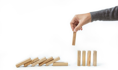 Social Distancing and quarantine impact on pandemic spread of a virus in population. Concept hand stopping falling wooden dominoes for containing corona virus or any virus or pandemic outbreak.