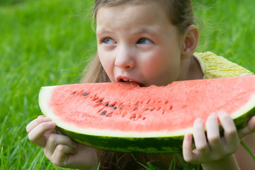 girl eating a sweet watermelon, on a background of green grass, close-up