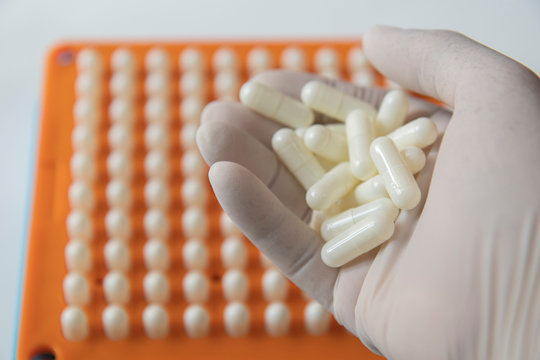 White Pill Capsules In White Medical Gloves