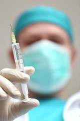 Coronavirus concept. A doctor in uniform and in a protective antiviral mask with a syringe.Medicine and health concept. Vaccination against the virus. Virus protection.Prevention of colds and flu.