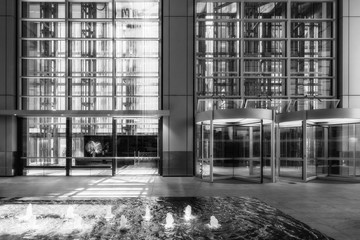 Strong light coming through the glazing of an high-rise office building lobby with a water fountain...
