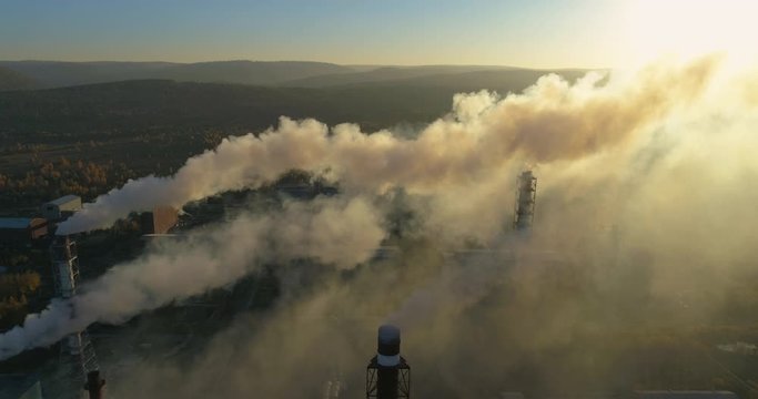 Aerial drone footage of steel factory smokestack during sunset time. Top view of metallurgical plant smoke coming from chimney. Sunset time with beautiful golden yellow lighting. 4K