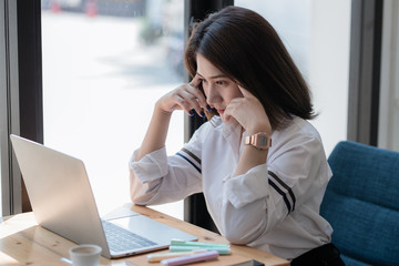 Obraz premium young woman using laptop computer while sitting at cafe background, technology and lifestyle. Beautiful young business woman looking at her laptop.