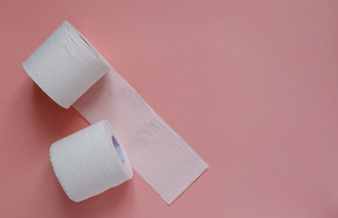 Lots of rolls of white toilet paper on a pink background. Panic, covid-19 concept. Horizontal orientation. View from above. Copy space.