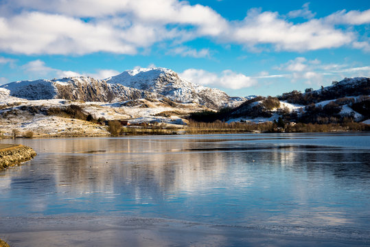 A scenic landscape view of mountains covered by snow from Edlandsvatnet lake, Algard, Norway, February 2018
