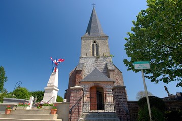 Fototapeta premium Eglise de village avec monument aux morts et drapeaux bleu blanc rouge. Jour férié