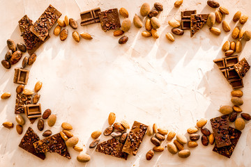 Chocolate frame. Broken slices and nuts on light background top-down copy space