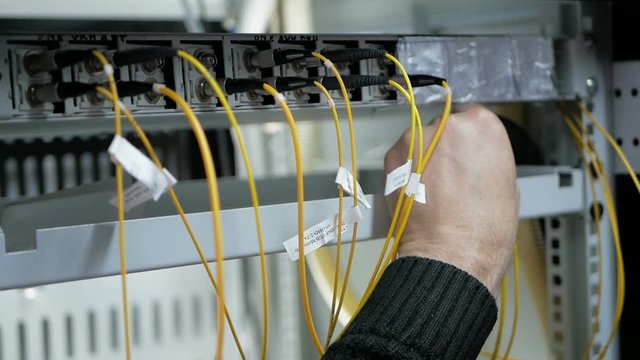 Pull-out shot of a optical fiber switchboard hub with a blurred technician working