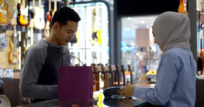 Young muslim man use smartphone paying over contactless transaction machine