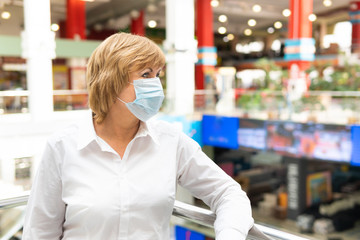 A woman in a virus mask walks around a public place in the city.