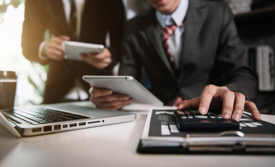 Obraz premium Close up Businessman and partner using calculator and laptop for calculation finance, tax, accounting, statistics and analytic research concept. in the office.
