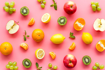 Colorful fruit pattern. Cut apple, kiwi, citrus on pink background top-down