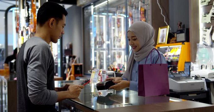 Young muslim man use smartphone paying over contactless transaction machine
