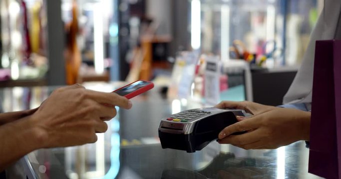 Young muslim man use smartphone paying over contactless transaction machine