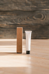 Cosmetic white tube and paper box on wooden table
