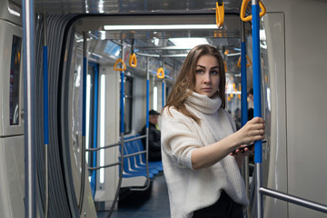 Portrait of female passenger using mobile phone in subway car. Young woman absorbed in her smartphone while traveling in metropolitan.