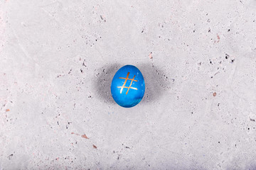 Blue egg with hashtag pattern on concrete surface
