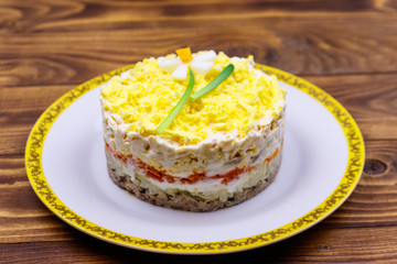 Traditional russian layered salad Mimosa with spring decoration Daffodil. Decoration is made of egg, green onion and carrot