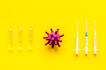 Corona virus Covid-19 - vaccine concept with syringe - on yellow background top-down pattern