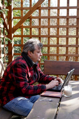 middle-aged man works at home-office in the backyard spring garden