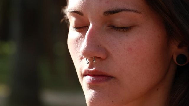 Contemplative young millennial girl face meditating outside. Pensive woman taking a deeb breath outdoors