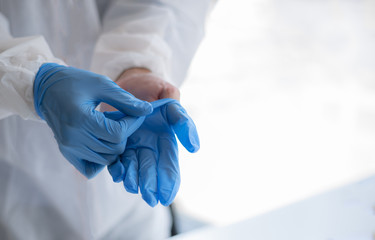 Human hands taking off blue disposable gloves.