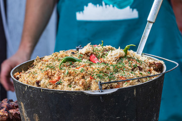 Culinary buffet with takeaway healthy food - plov, rice, meat, pepper, spices, grilled vegetables. Fish and meat on the street, food market, festival, event. Kitchen in the open air.