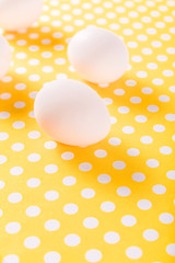 White chicken eggs on a yellow background with a polka dot pattern