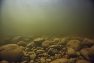 Fototapeta na wymiar stones at the bottom underwater landscape, abstract blurred under water background