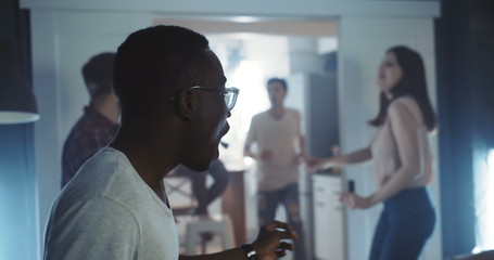 Happy young smiling African man dancing with friends at multiethnic party, celebrating holidays together slow motion.