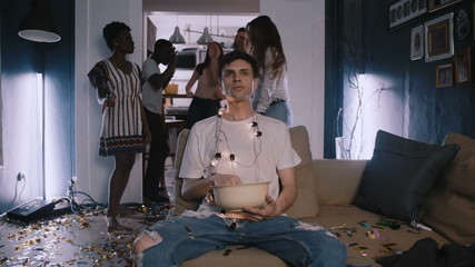 Camera zooms in on young Caucasian man addicted to movies, happy dancing party crowd in the...