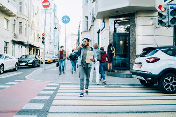 Man speaking on mobile phone crossing pedestrian passage in city - obrazy, fototapety, plakaty