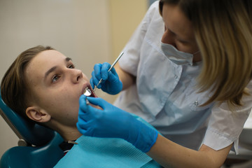 Dentist woman doing teeth checkup of man in a dental chair. Stomatology medicine concept.