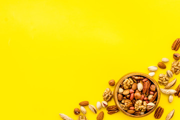 Mixed nuts in bowl - healthy snack - on yellow background top-down frame copy space