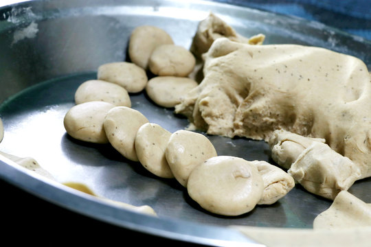 Preparation of AlooParatha / parantha / roti / chapati Punjab, North India. Female hand rolling whole wheat dough with mashed potato stuffing with rolling pin. Indian side dish raita, dal makhani.