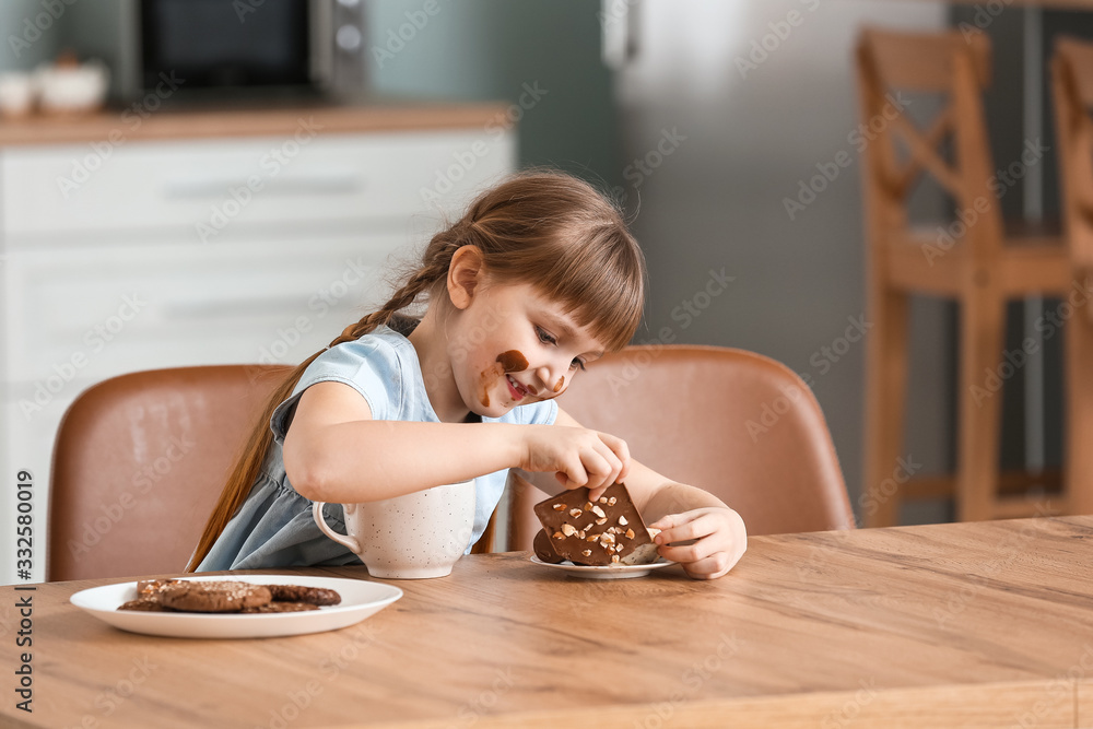 Wall mural cute little girl eating chocolate in kitchen