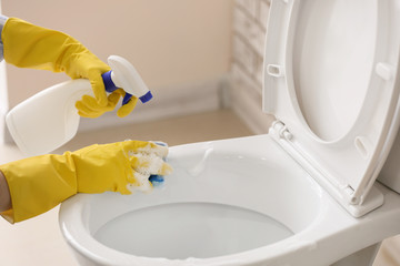 Woman cleaning toilet bowl in bathroom