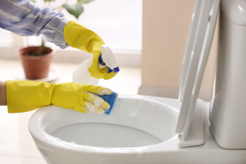 Woman cleaning toilet bowl in bathroom